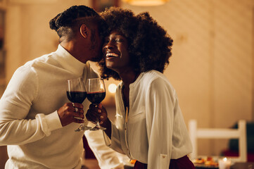 African american couple having romantic date at home while drinking wine and kissing