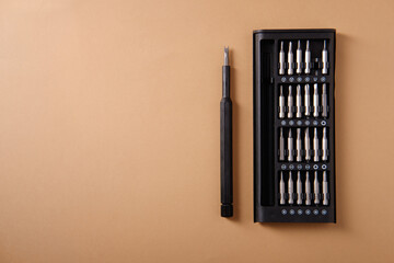 A set of precision screwdrivers for disassembling phones, on a brown background
