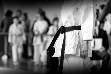 A martial arts athlete in a white kimano with a black belt is preparing for a fight. Black and...