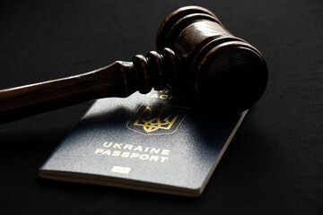 Biometric Ukrainian passport and judge's gavel lie on a black background, law in Ukraine
