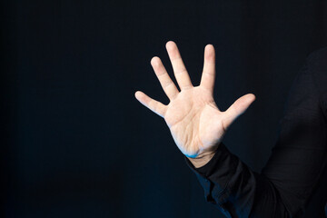 Business person with five fingers raised up isolated on black. Stop gesture with copy space.