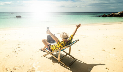 Man in the summer hat , a businessman, digital nomad working with laptop and mobile phone on the...