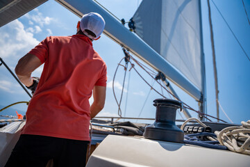 Mans pulling winch rope on sailing boat