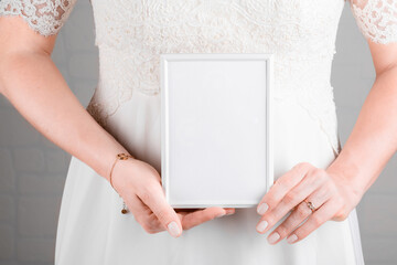 Bride holding wedding stagionery invitation card mockup 5x7 on white wall background. Minimal stile...