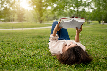 Student Young Lady Reading Book Lying On Green Grass Outdoor