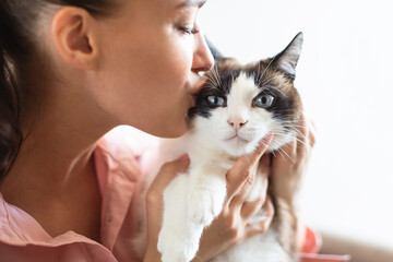 Young lady kissing her cute cat over white studio background