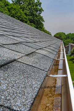 Clogged Gutters That Had Not Been Cleaned Last Fall.  Rainwater Fills And Gutters Overflow With Rain Water Water Can Damage The House Siding, A Wet Basement, And Erosion In The Landscaping