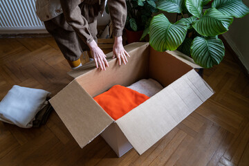 Women hands put different clothes in cardboard box for charity, recycling, fair, flea market....