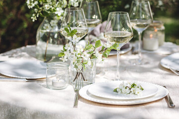 Rustic elegant eco friendly zero waste trendy wedding reception table decor with fresh spring apple cherry flowers in bloom. Beautiful marriage decoration, holiday event outdoors in the family garden