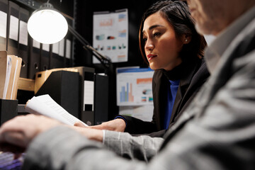 Accounting business executives coworkers imputing bookkeeping analytics data on laptop. Teamworking elderly businessman and asian collegue in administrative archival depository storage office