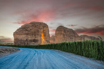 Sunset sandstone elephant rock erosion monolith standing in the desert, with road in foreground, Al Ula, Saudi Arabia