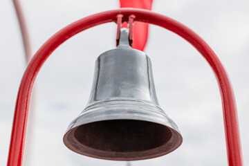 Bronze old bell on red holder in a boat - Close up