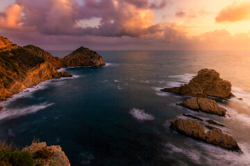 amanecer con nubes de colores en la playa con rocas