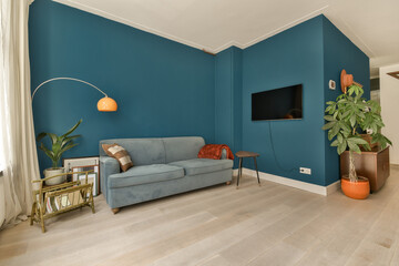 a living room with blue walls and white trim on the walls there is a grey couch in front of it