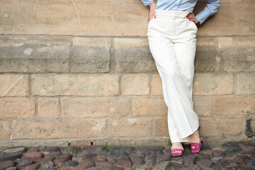 a successful young woman in white trousers and a blue shirt. the woman is leaning against the wall....