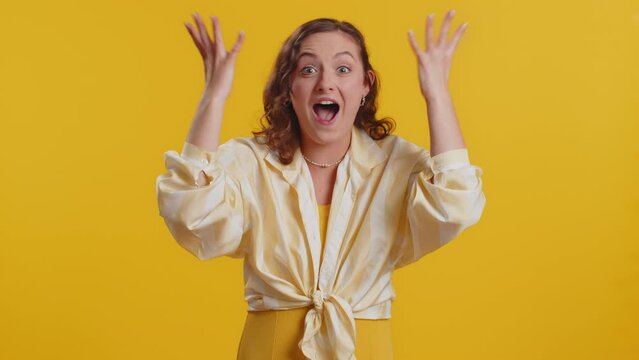 Excited amazed woman touching head and showing explosion, looking worried and shocked, celebrating success idea. Looking surprised of win wow brunette girl isolated alone on yellow studio background