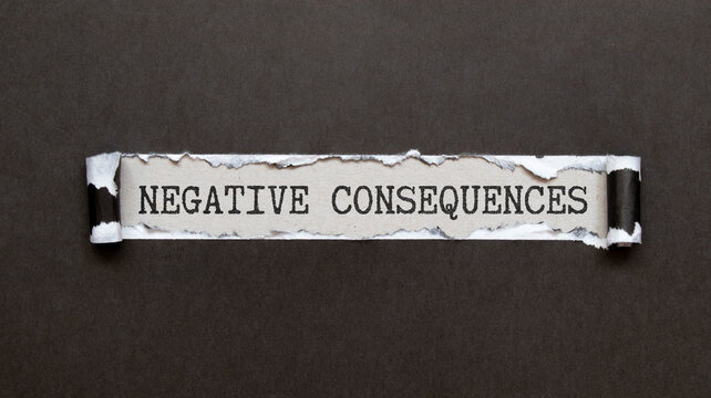 Closeup on businessman holding a card with text NEGATIVE CONSEQUENCES, business concept
