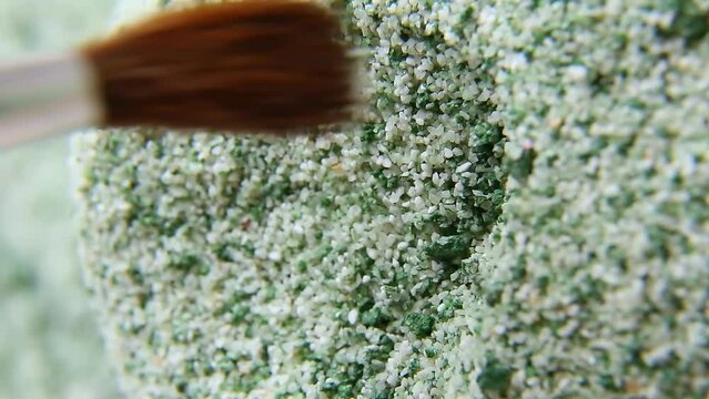 Pale green powder is dug with a brush. The green crumbly substance is stirred with a brush, the colored substance is dug out with a brush. Macro. ASM video