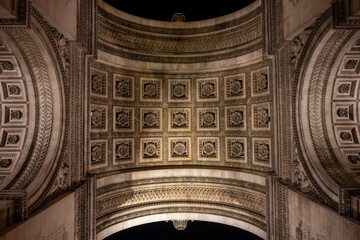 Fototapeta na wymiar Detailed view of Arc de Triomphe from bottom by night, Paris, France