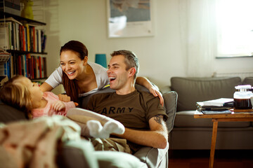 Father reuniting with his wife and daughter at home after deployment - obrazy, fototapety, plakaty