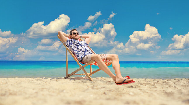 Young man sitting at a deck chair by the sea