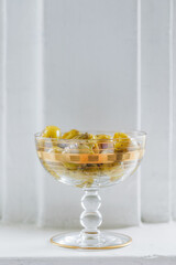 grilled green olives in vintage gold ice cream glass dish, white background