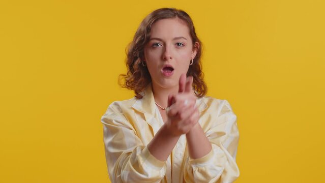 Young woman pointing around with finger gun gesture, looking confident, making choice, shooting killing with hand pistol right on target. Girl isolated alone on yellow studio background. Lifestyles