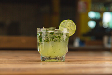 Mojito with mint, lime, and tequila on a wooden table in a restaurant.




