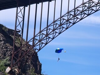 Base jumper parachutes by bridge.