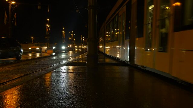 Tram traveling along night illuminated road. A view of public tram traveling through the buildings of the night city.