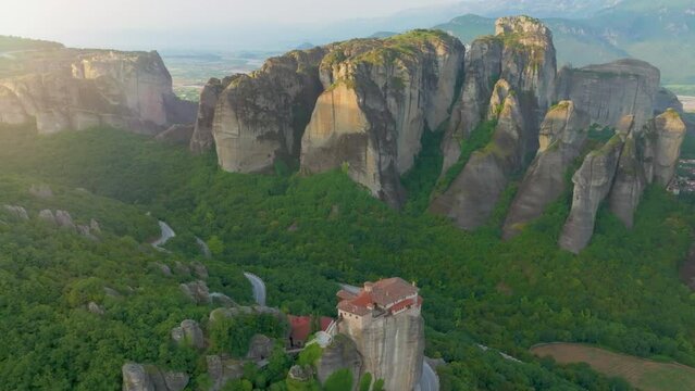 Epic aerial view of a valey Meteora with clifs  illuminated by warm light of sun and Holy Monastery of Rousanos - Saint Barbara complex. A UNESCO World Heritage Site. Greece.