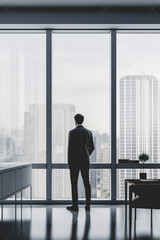Fototapeta premium silhouette of a man standing in front of a window with a city