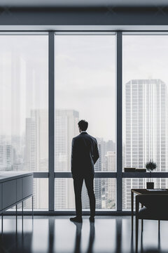 silhouette of a man standing in front of a window with a city