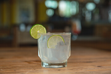 Gin and tonic on a wooden table with a slice of lemon.




