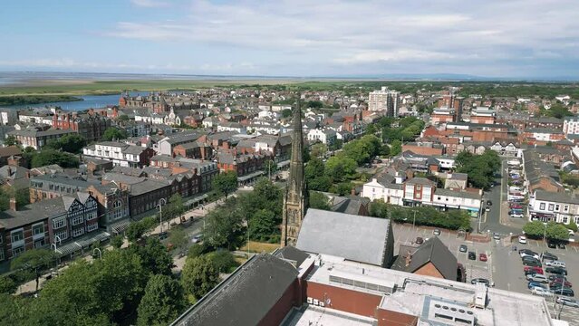 Southport, Lancashire, UK, June 19, 2023; Mid-level aerial orbital clip video footage of St George's URC Church with tall spire on Lord Street in Southport, England