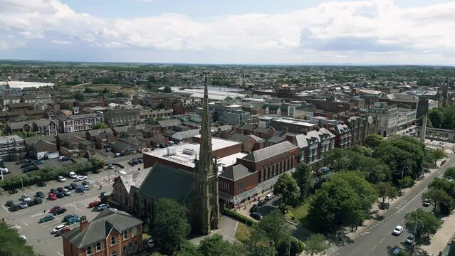 Southport, Lancashire, UK, June 19, 2023; Mid-level aerial orbital clip video footage of St George's URC Church with tall spire on Lord Street in Southport, England