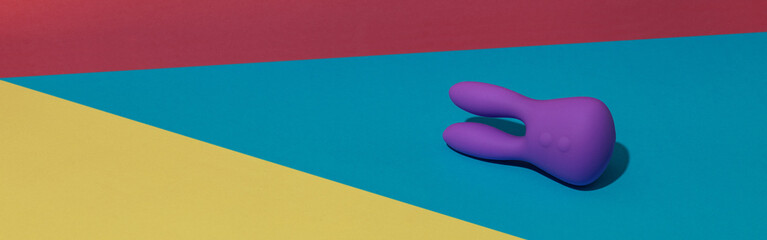 Violet dildo vibrator for clitoris on colored background with contrast shadows. Sex toy for adult