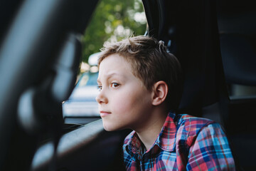 Handsome caucasian boy travelling by car sitting in child seat.Recreation concept