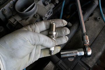 car maintenance, spark plug change operation of the internal combustion engine, in the workshop during the replacement, maintenance of the spark plugs in the heart of the engine. hands at work