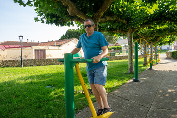 Hombre de la tercera edad haciendo deporte en una máquina para ejercitar las caderas.