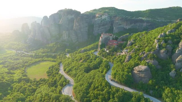 Epic aerial view of a valey Meteora with clifs  illuminated by warm light of sun and Holy Monastery of Rousanos - Saint Barbara complex. A UNESCO World Heritage Site. Greece.