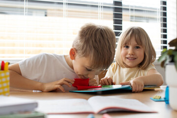 Fototapeta premium Brother and sister together amicably read an educational book. The concept of a happy childhood.
