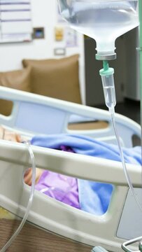 fluid intravenous drip saline dropping continuously rate at the hospital ward. Patient lay on bed on blurred background.