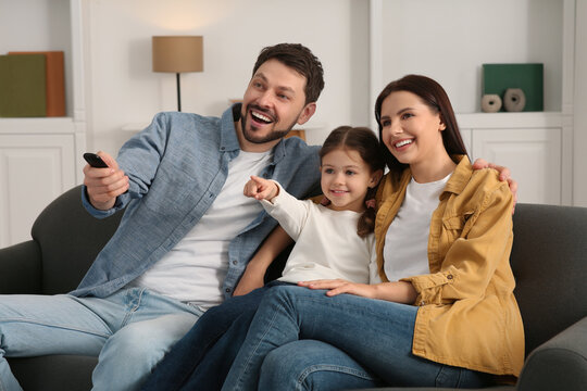 Happy family watching movie at home. Father changing TV channels with remote control