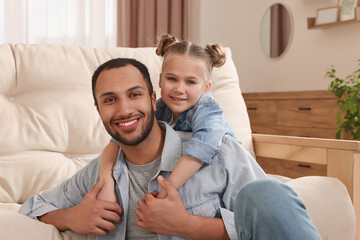 Little girl with her father spending time together at home. International family