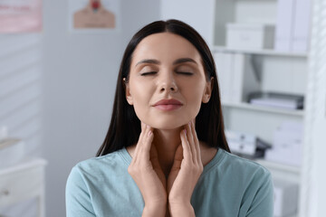 Endocrine system. Young woman doing thyroid self examination indoors