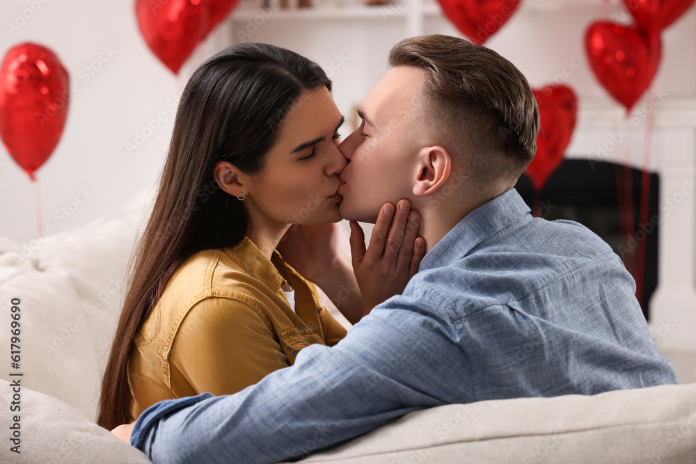 Poster Lovely couple kissing on sofa indoors. Valentine's day celebration