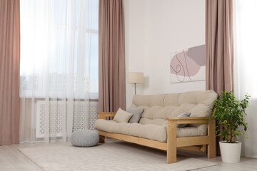 Stylish room interior with comfortable sofa, houseplant and elegant curtains