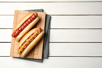 Delicious hot dogs with mustard and ketchup on white wooden table, top view. Space for text