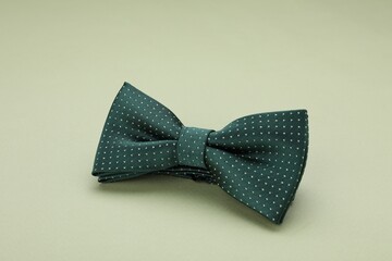 Stylish bow tie with polka dot pattern on pale green background